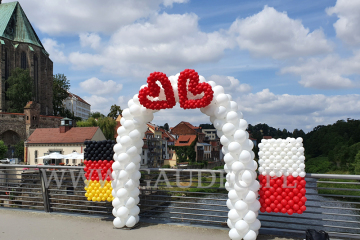Brama z balonów z flagami Polski i Niemiec.